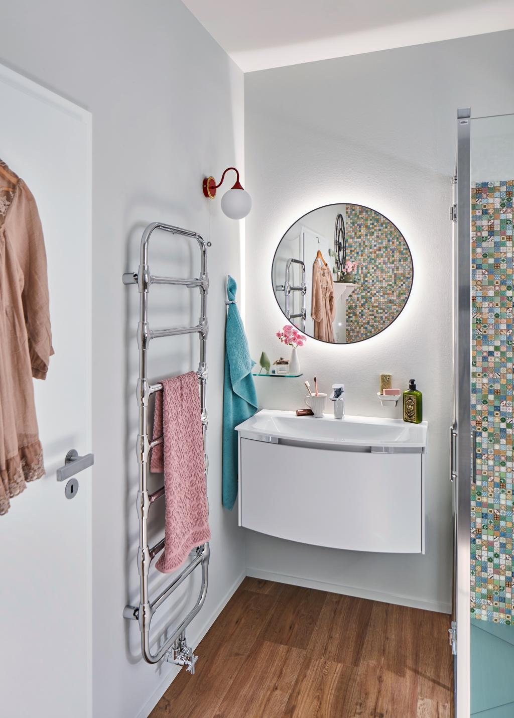 Kleines Bad mit Waschtisch und rundem Spiegel sowie Handtuchhalter-Heizung