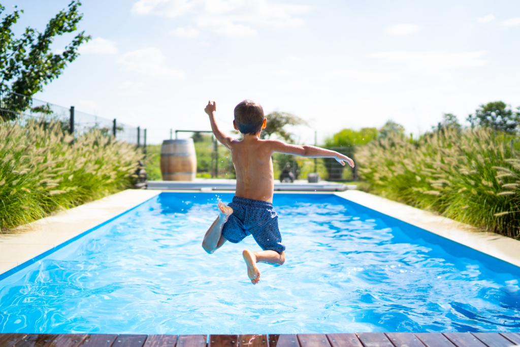 Junge springt in Pool in Garten