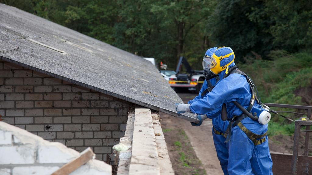 Männer in Schutzanzügen sanieren Dach mit Asbest