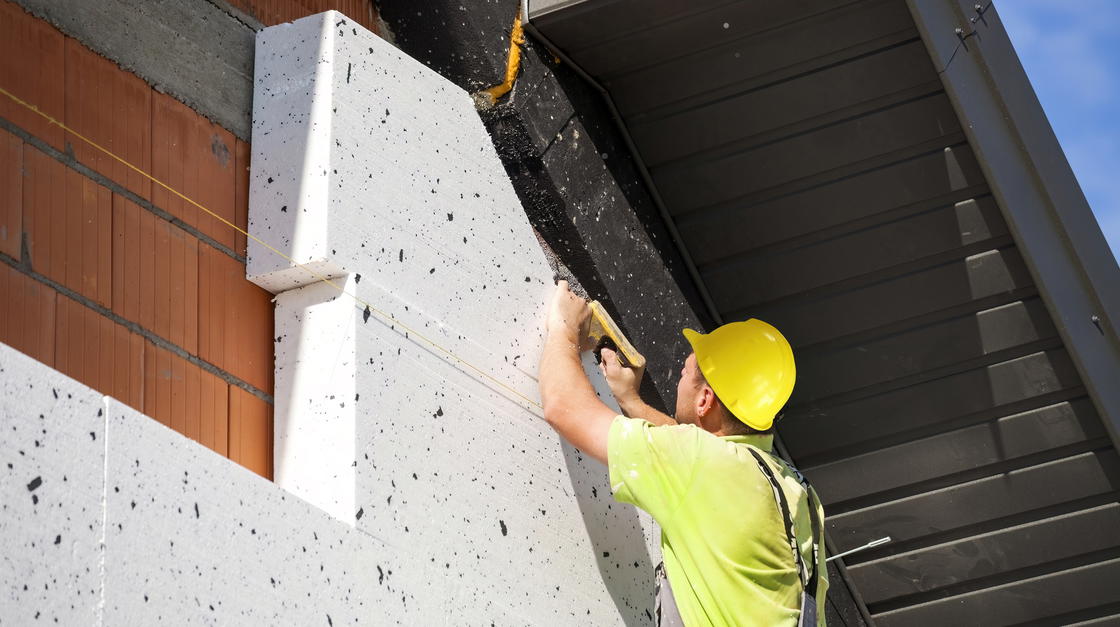 Mann dämmt Fassade mit Polystyrol