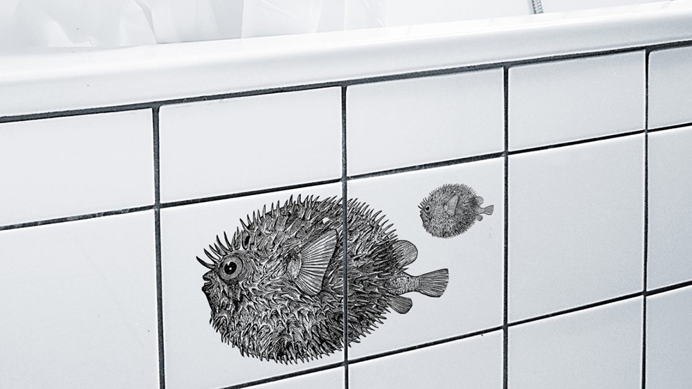 Fliesenaufkleber in Fischform am Rand einer Badewanne mit weißen Fliesen