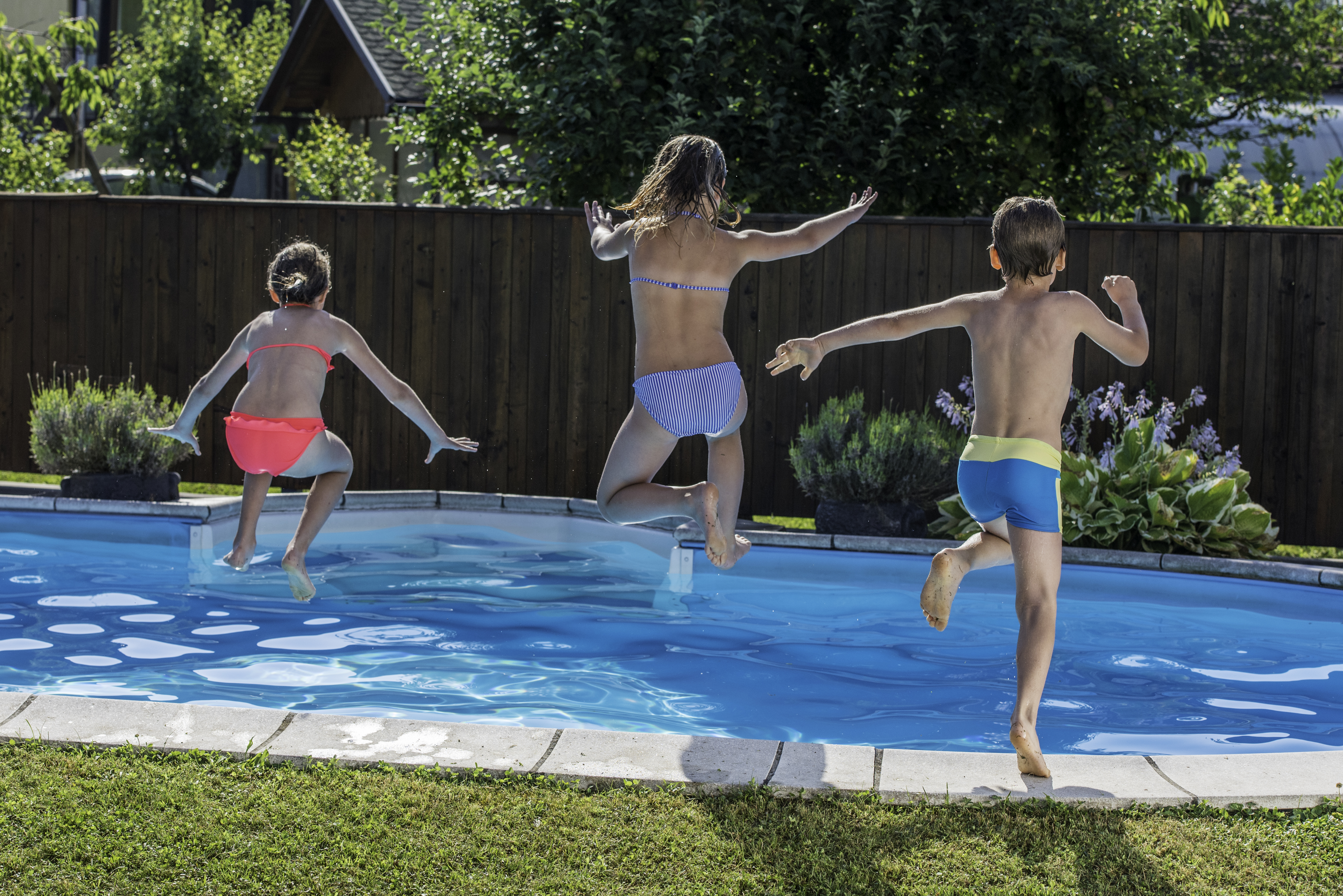 Kinder springen in einen Pool im Garten