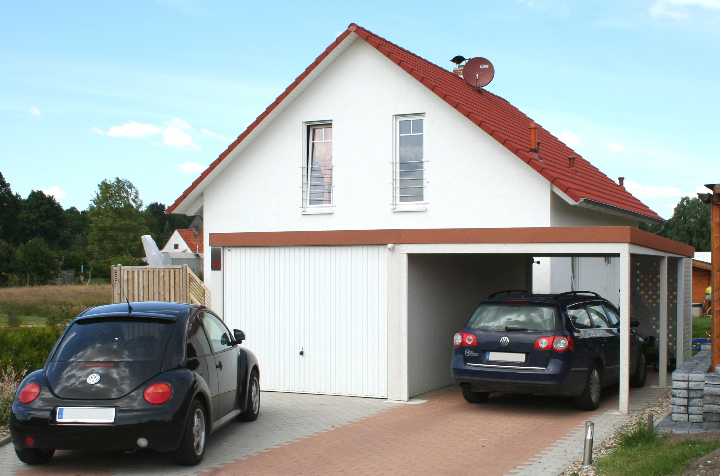 Garage mit Carport udn Autos vor Einfamilienhaus.