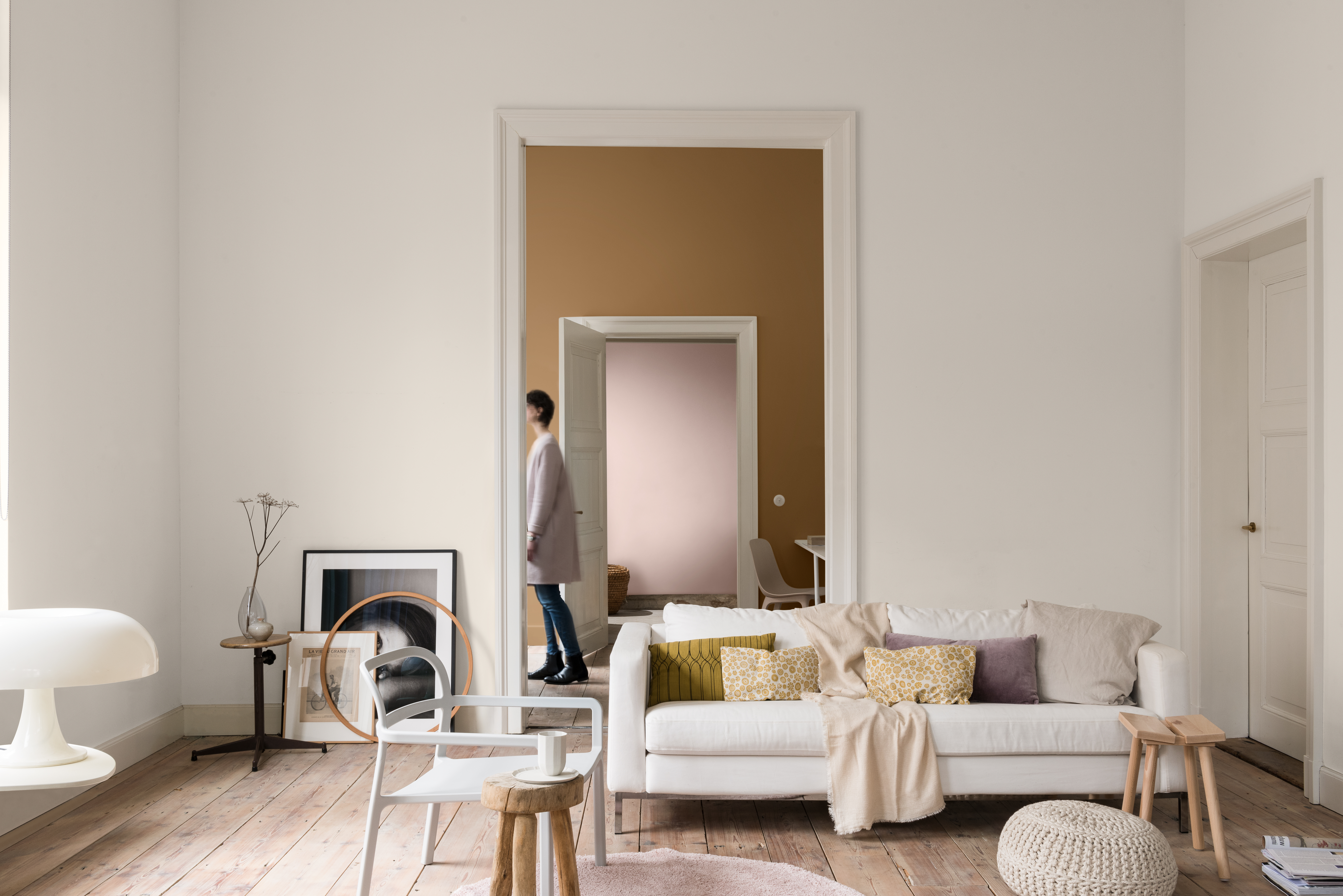 Ineinander übergehende Zimmer mit unterschiedlicher Wandfarbe mit Sessel, Sofa, Wolldecken und Kissen.