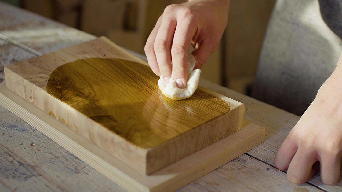 Stück Holz, das mit Holzöl behandelt wird