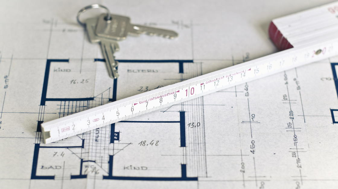 Bauplan mit Zollstock und Wohnungsschlüssel