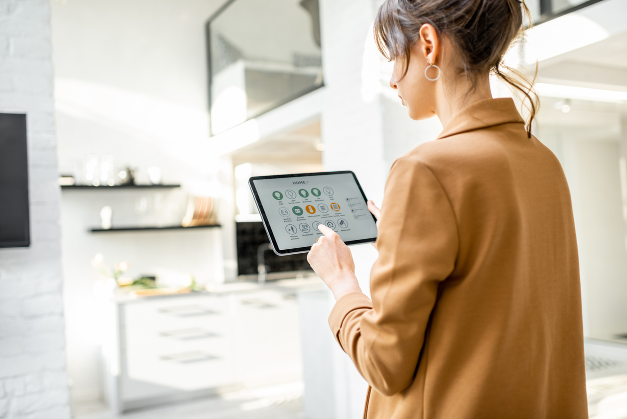 Junge Frau kontrolliert Smart Home mit Tablet