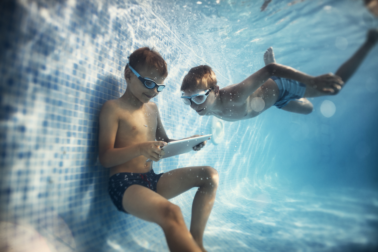 Zwei Jungs spielen mit Tablet in Pool