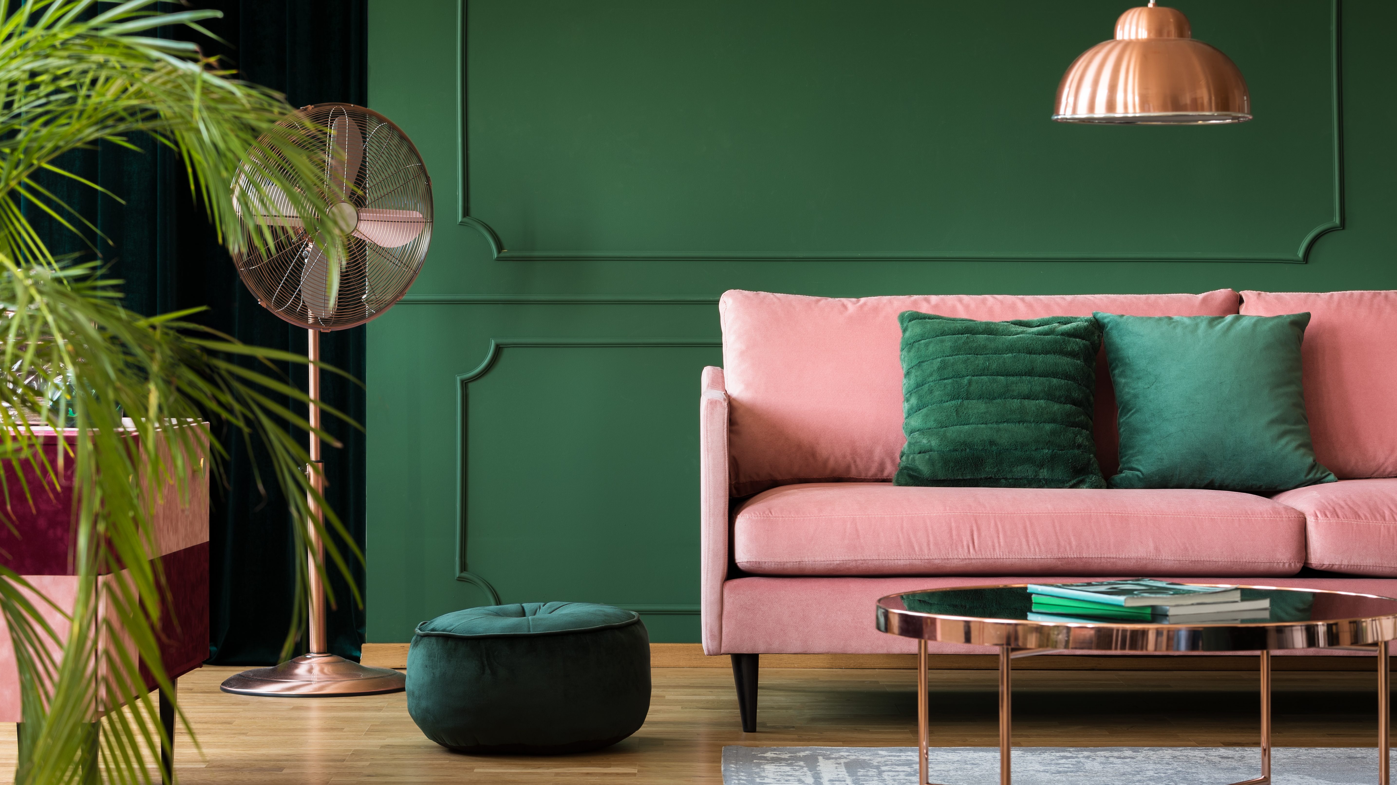 Rosafarbenes Sofa vor dunkelgrüner Wand