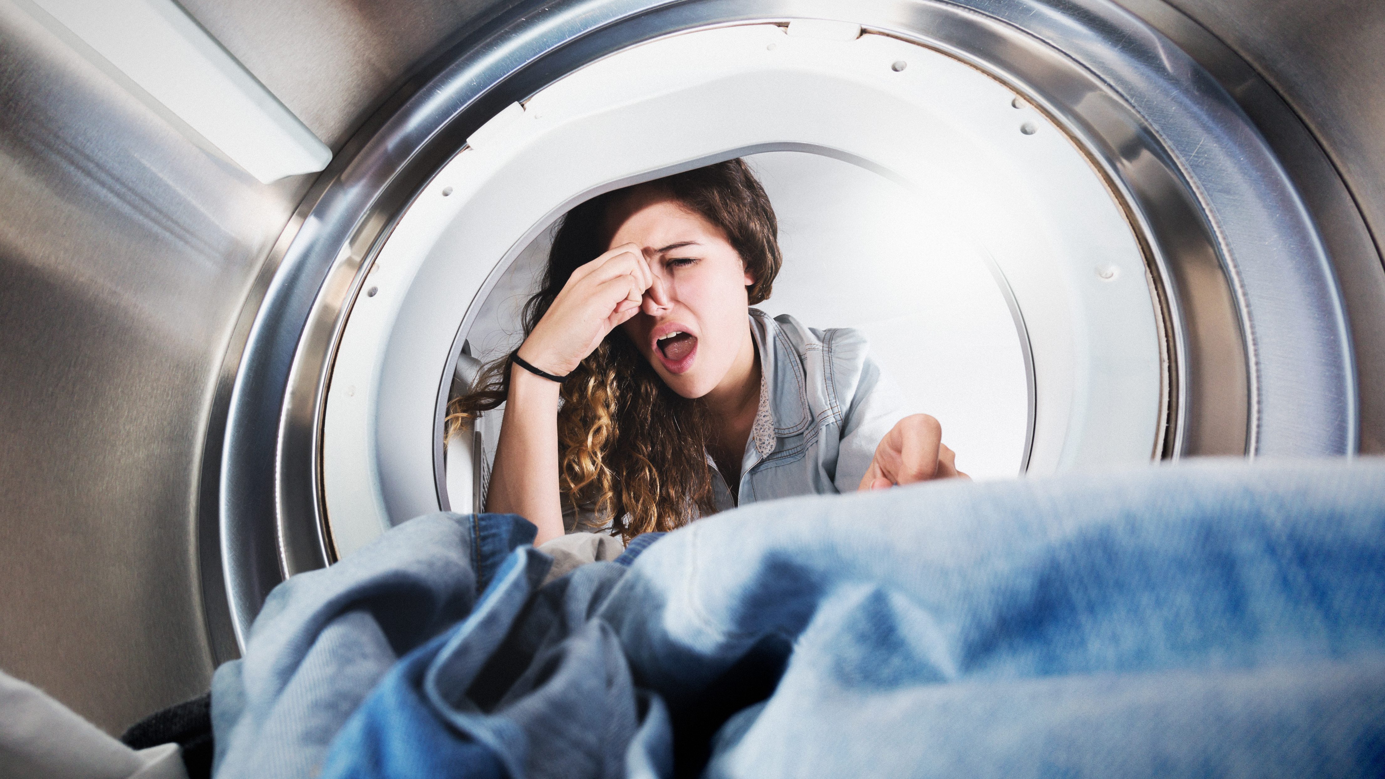 Frau guckt in stinkende Waschmaschine
