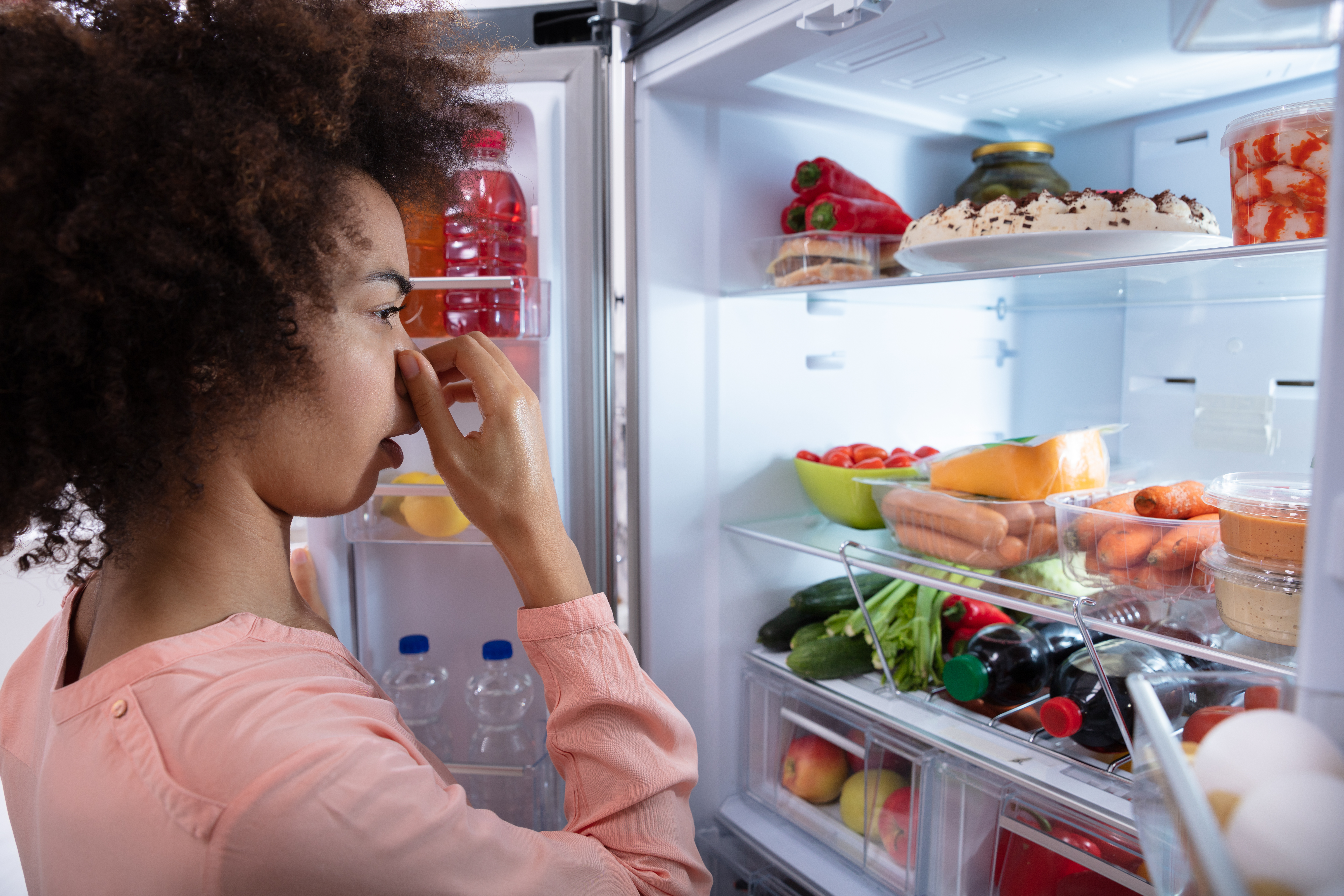 Frau öffnet stinkenden Kühlschrank