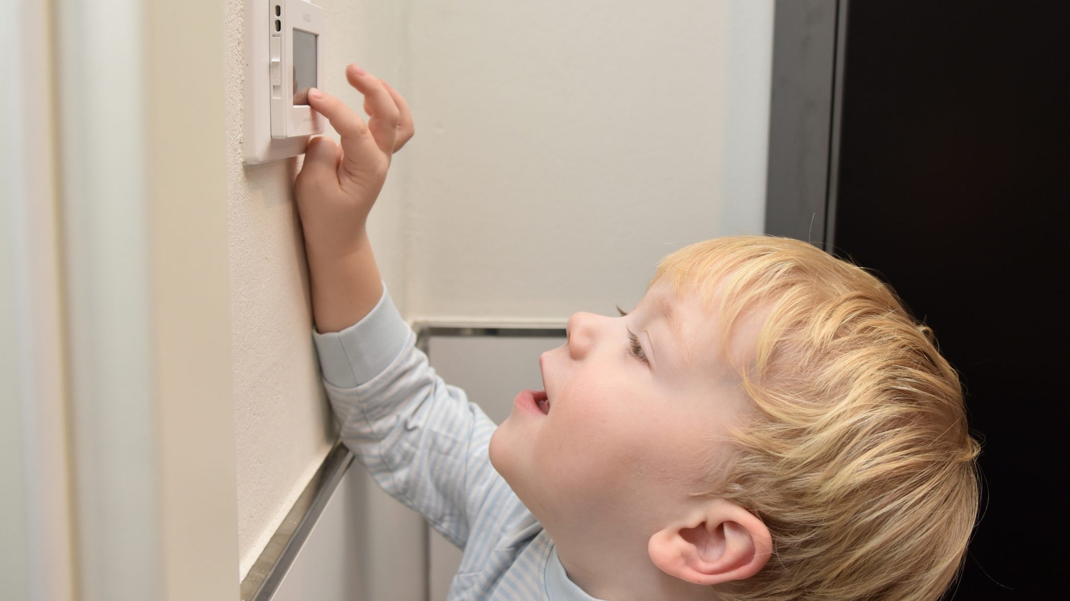 Ein kleiner Junge bedient den Temperaturregler einer Fußbodenheizung