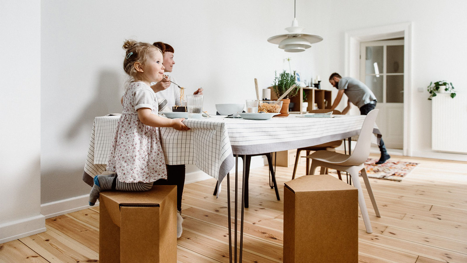 Familie am Küchentisch sitzt auf Hockern aus Pappe