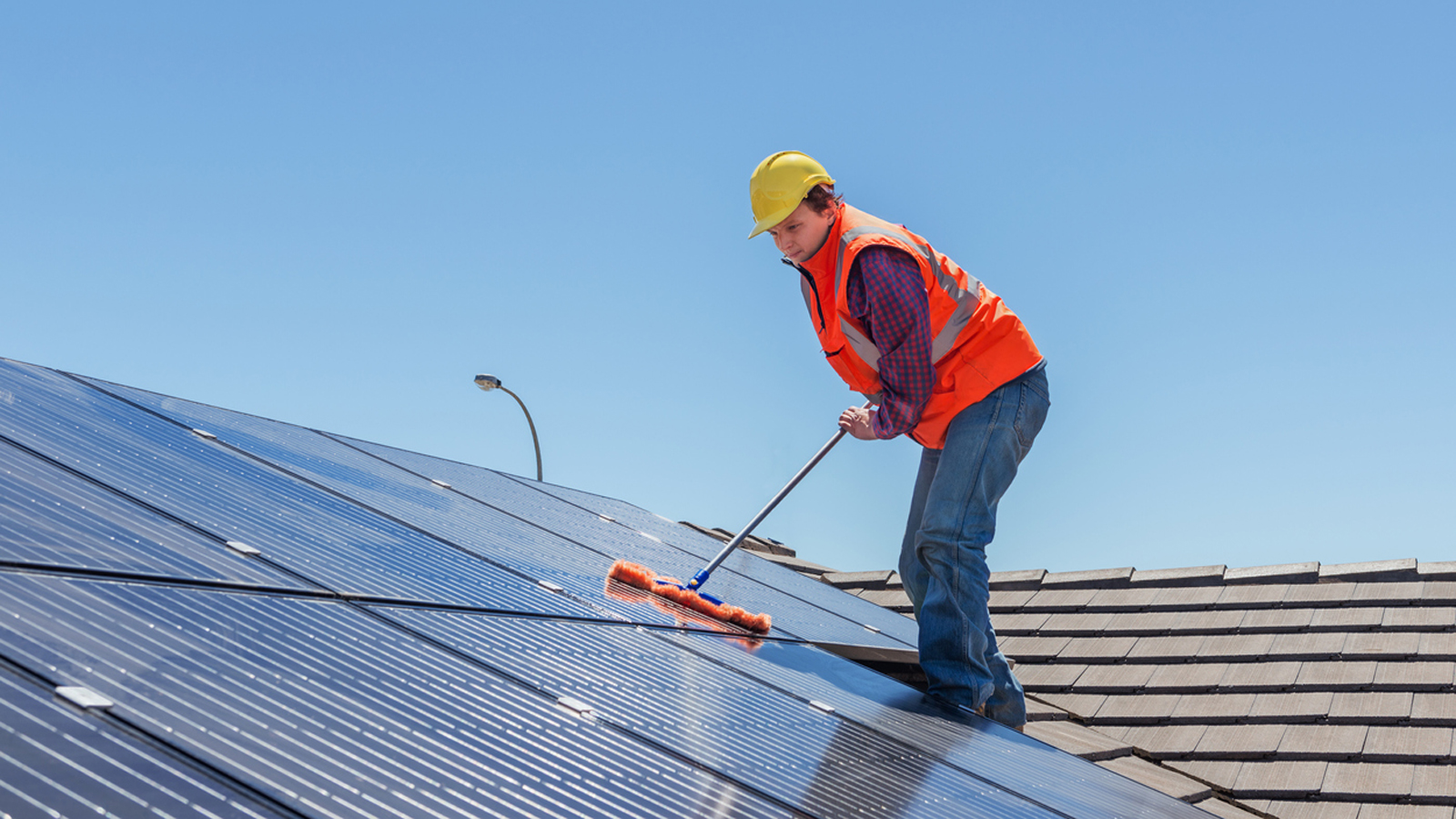 Mann reinigt Solaranlage auf einem Dach