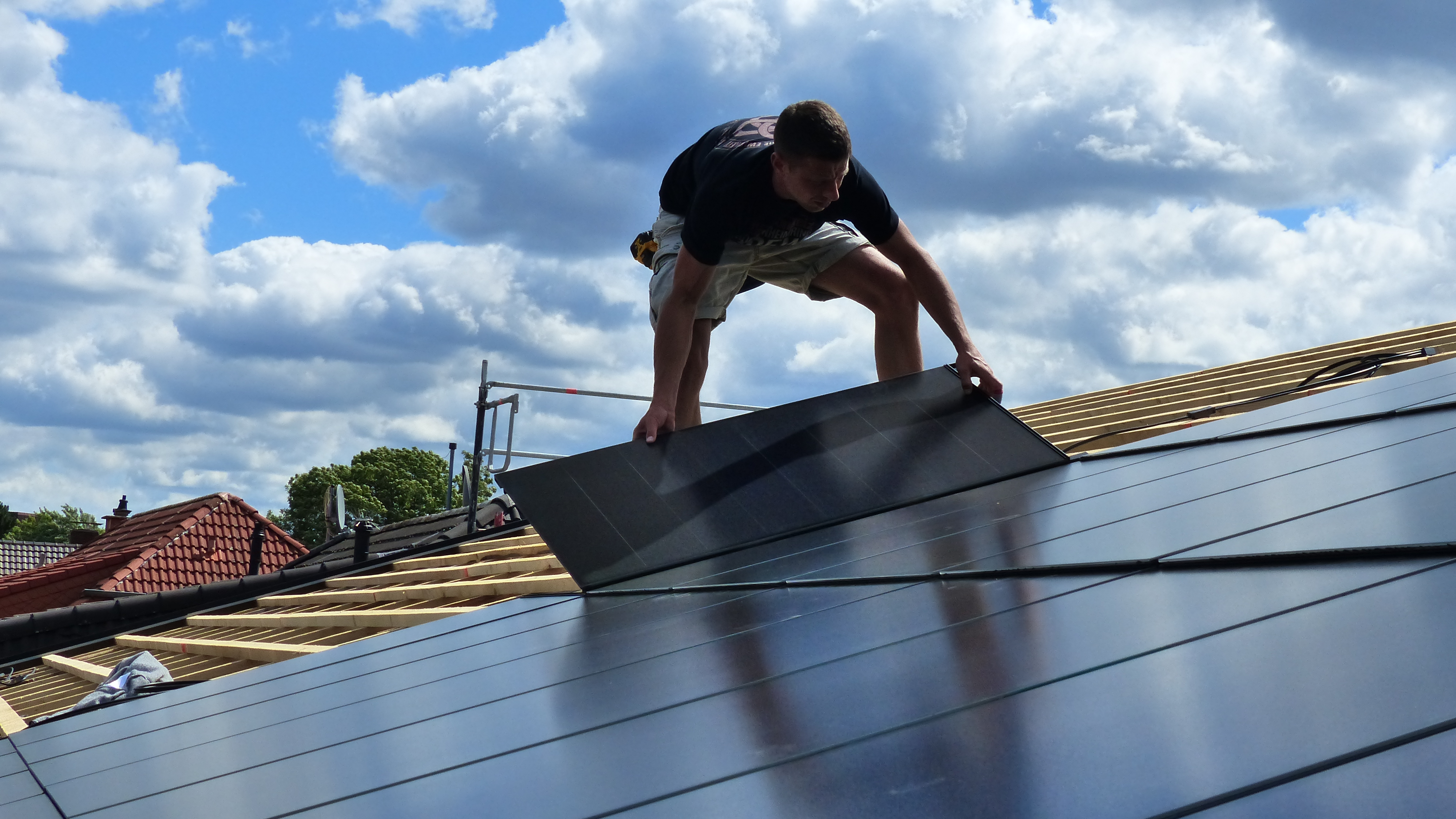 Solardachziegel: Mann deckt Dach mit -PV-Indach-Modul ein.