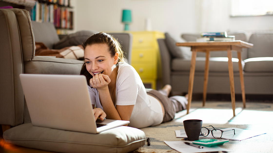 Frau liegt auf dem Fußboden vor ihrem Laptop
