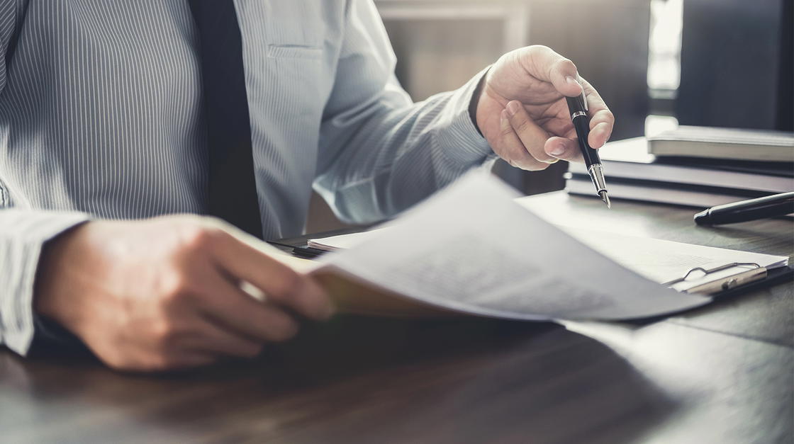 Mann mit Unterlagen und Stift in den Händen