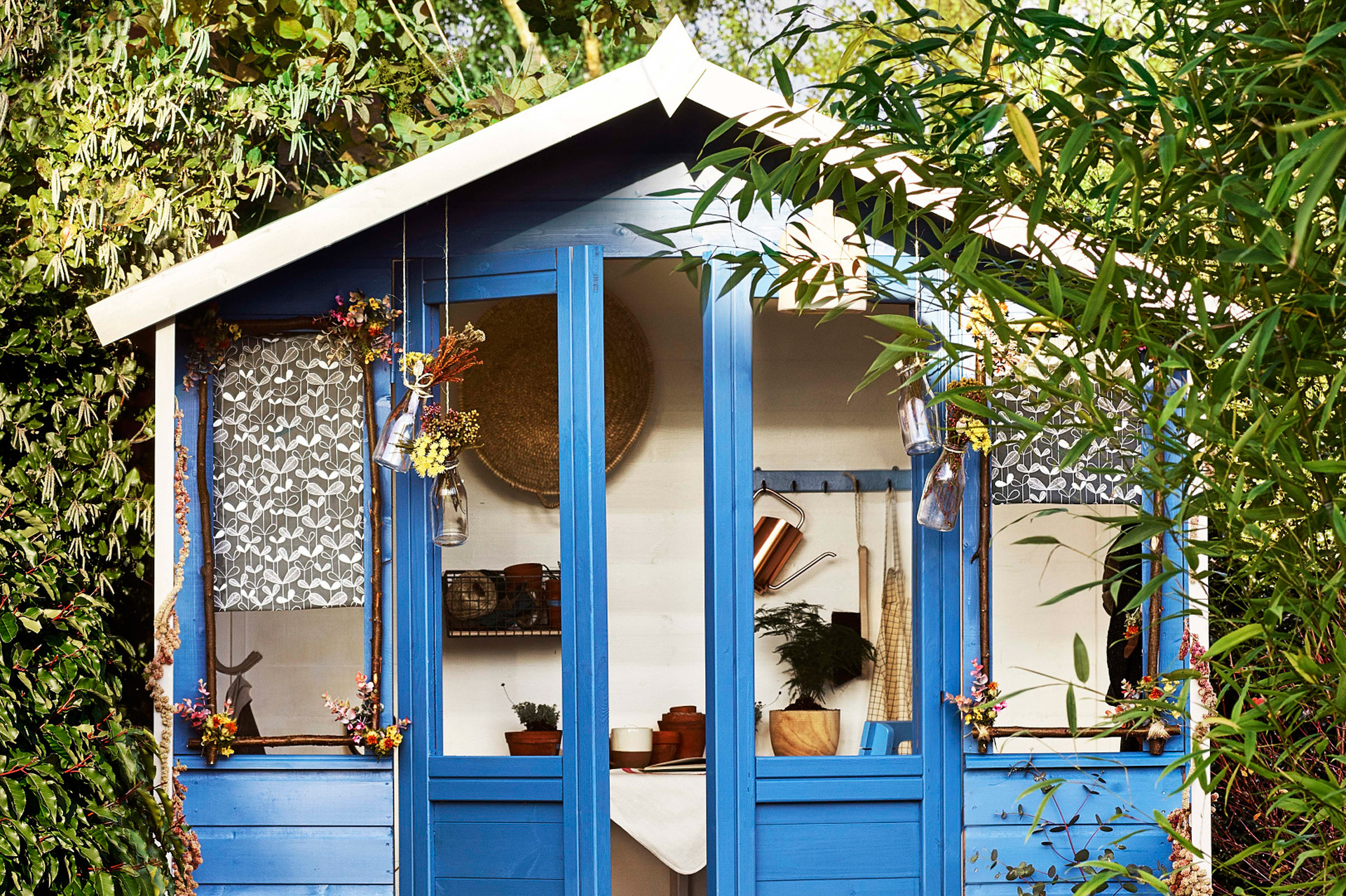 Blau gestrichenes Gartenhäuschen mit geöffneter Doppeltür