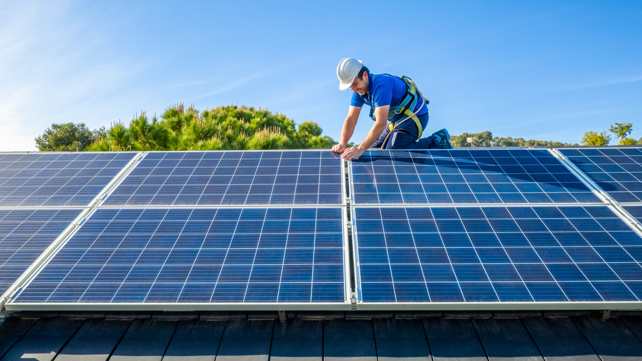 PV-Anlage Anmeldung: Mann installiert PV-Solarmodule auf einem Hausdach.