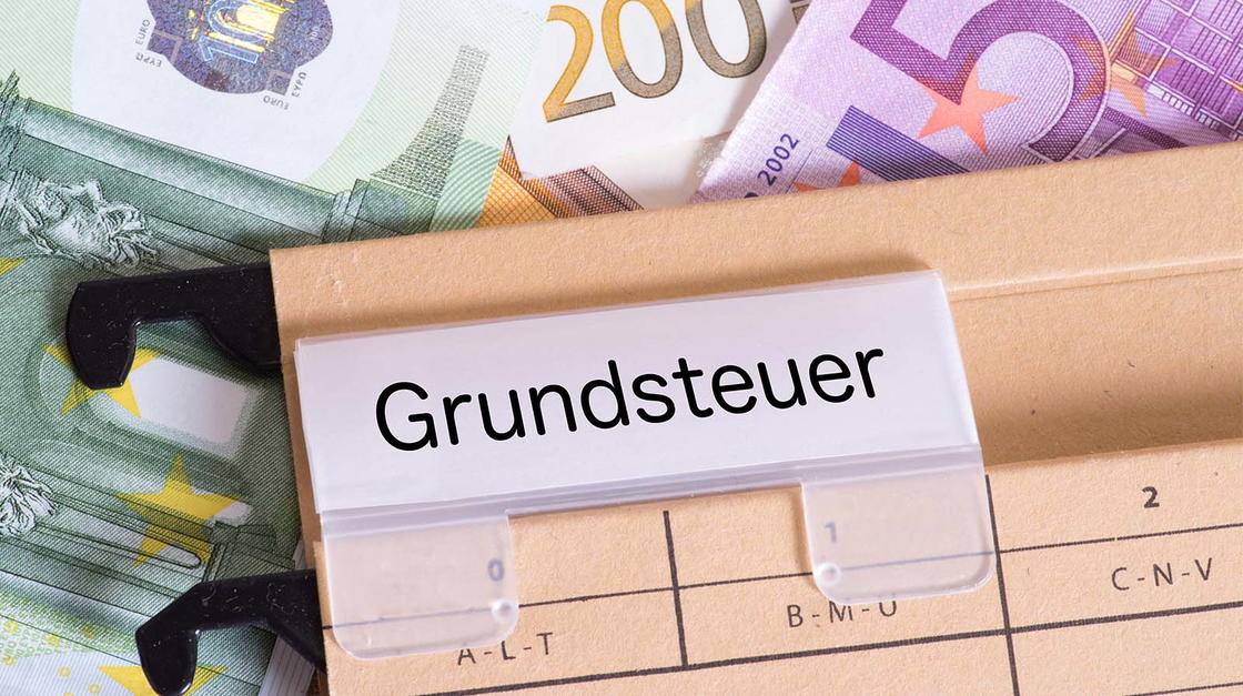 Mappe auf der Grundsteuer steht mit Geldscheinen