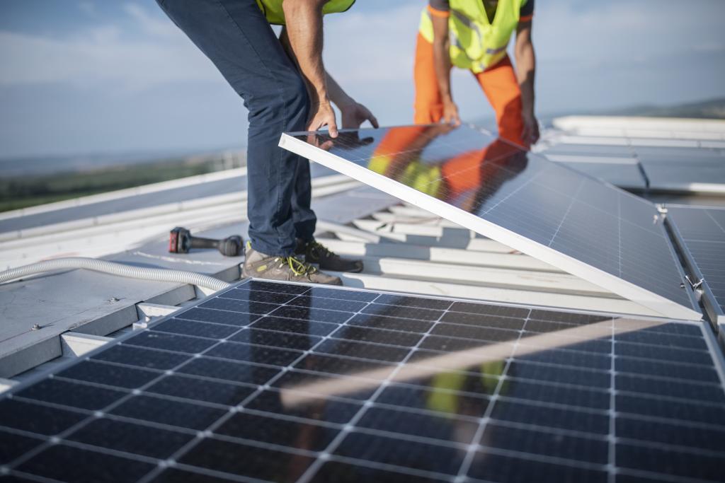 Zwei Ingenieure, die Sonnenkollektoren auf dem Dach installieren