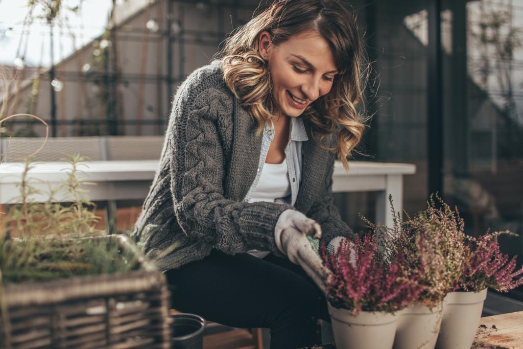 Frau bepflanzt Balkonkübel mit Heidekraut