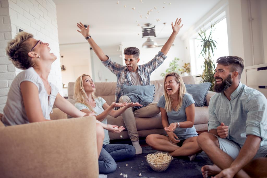 Eine Gruppe von Freunden sitzt im Wohnzimmer und hat Spaß