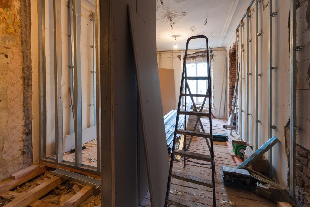 Einblick in einen Wohnraum während der Sanierung mit Baumaterialien, Gipskartonplatten und einer Leiter