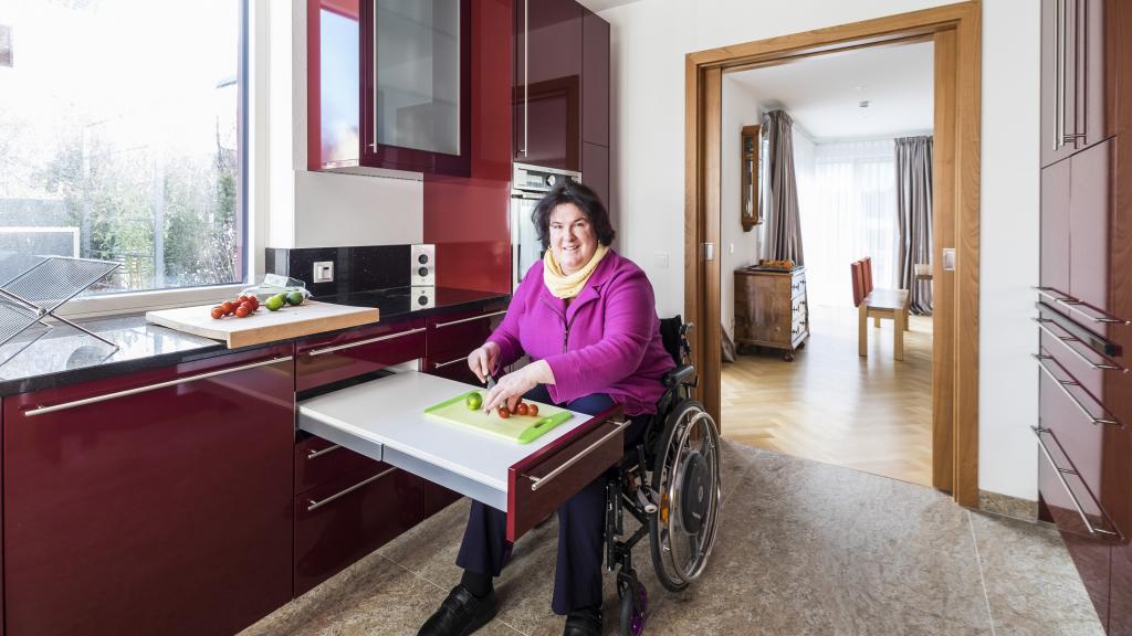 Frau im Rollstuhl sitzt in ihrem barrierefreien Haus.