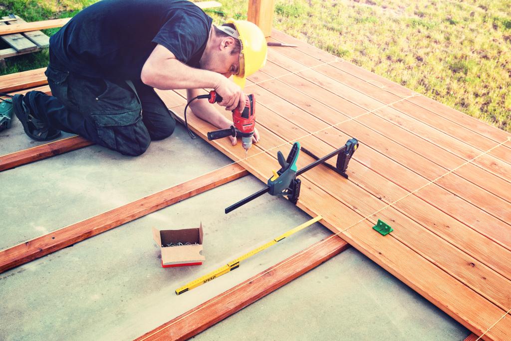 Handwerker verlegt Holzdielen auf einer Terrasse