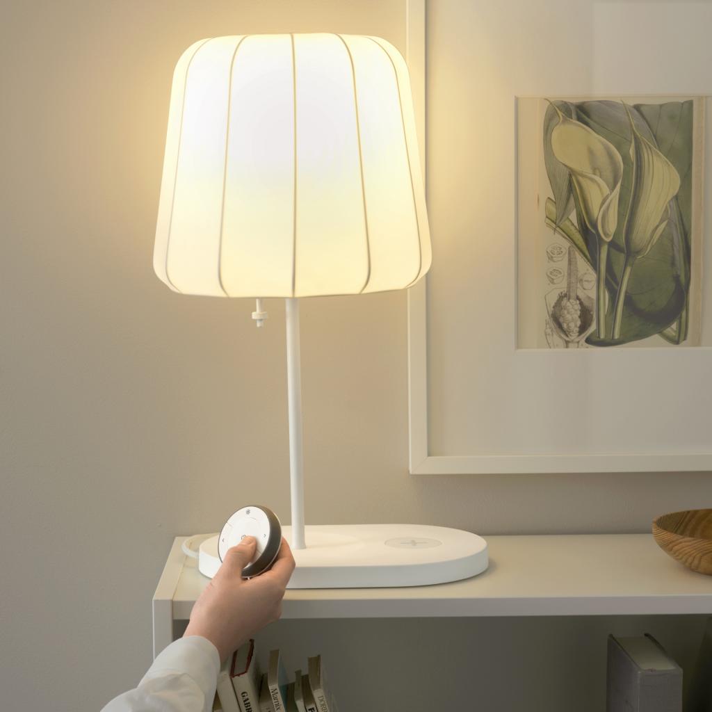 Hand drückt auf Fernbedienung für Lichtsteuerung von Ikea