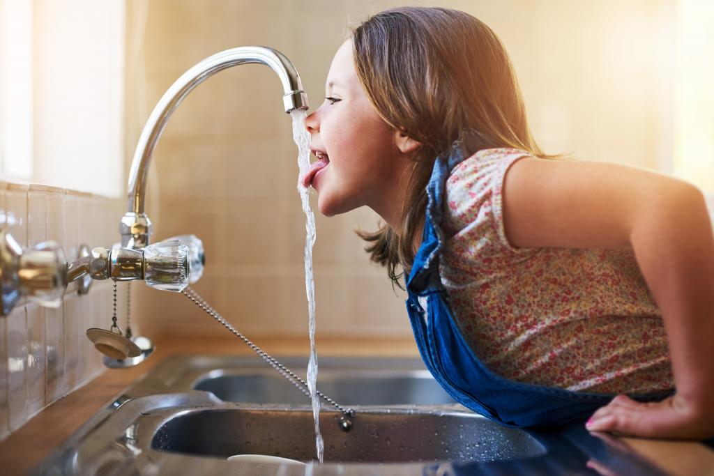Kind trinkt Wasser aus Wasserhahn