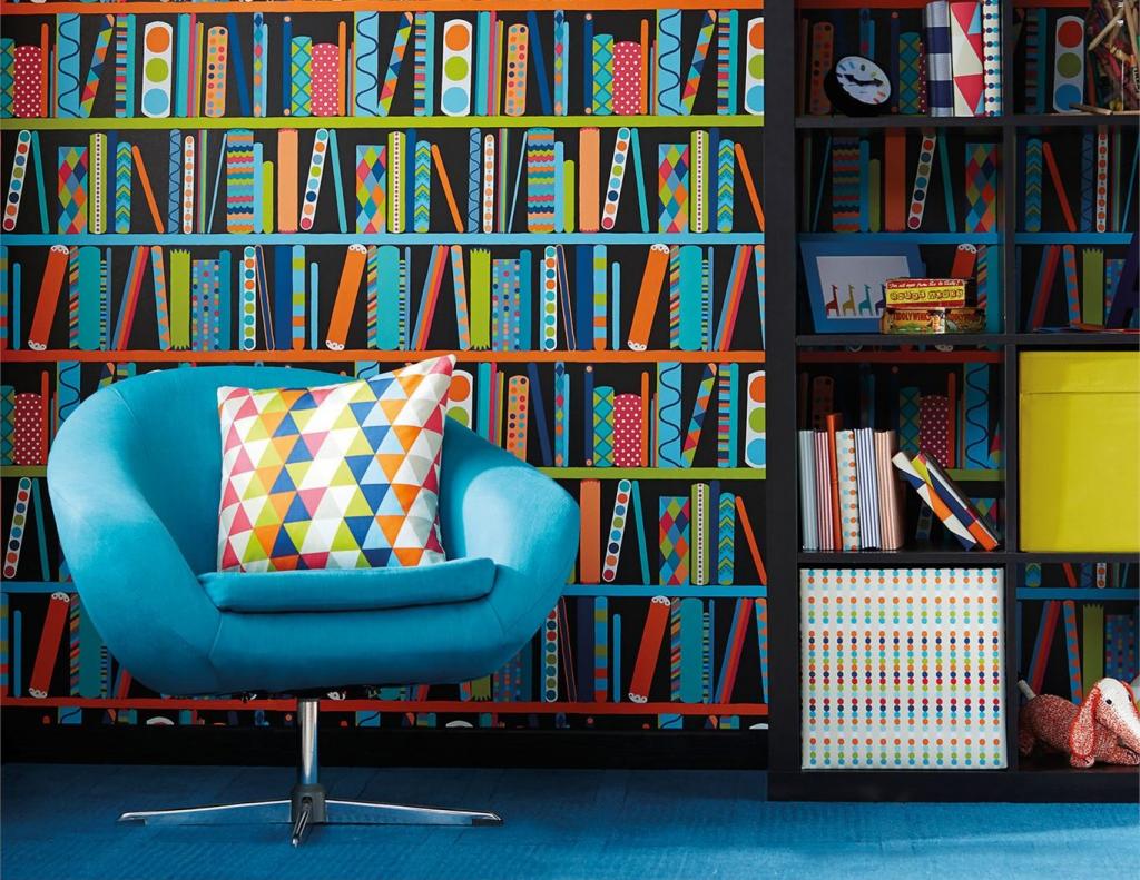 Blauer Sessel vor Tapete mit Büchermuster.