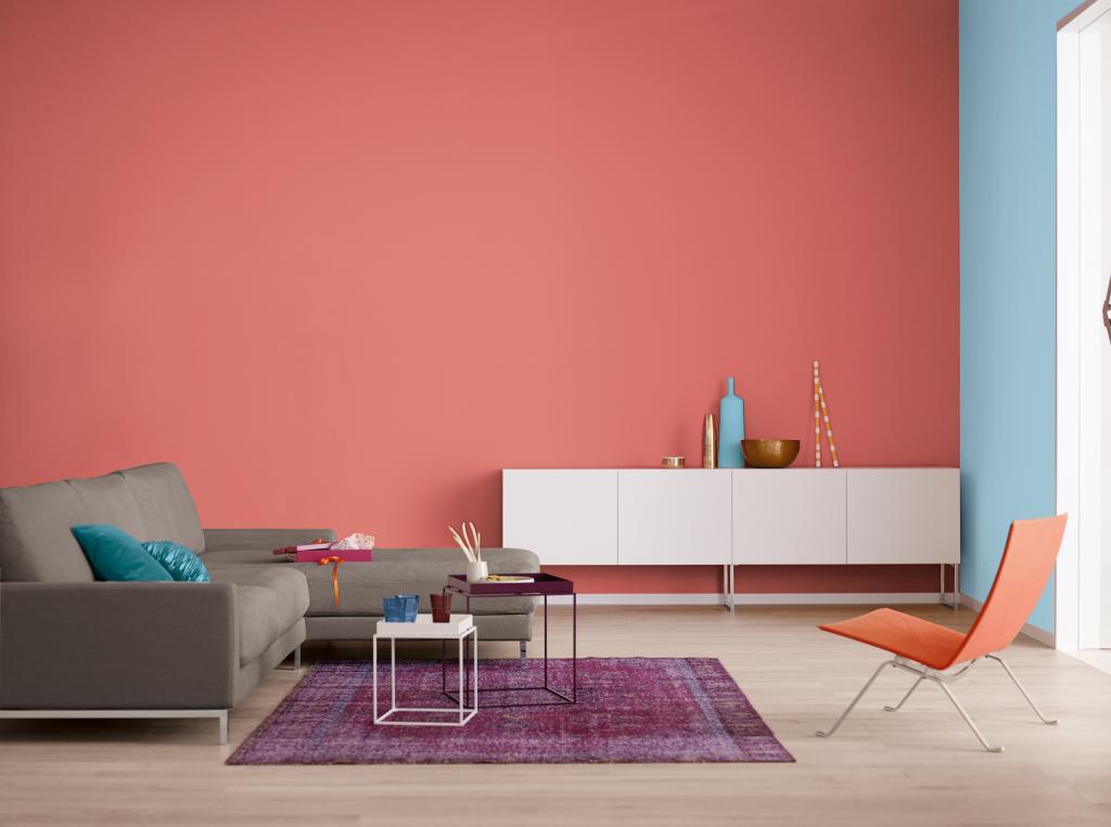 Modernes Wohnzimmer mit Beistelltischen, Sideboard, Sessel und Teppich vor rot und Himmelbalu gestrichenen Wänden.