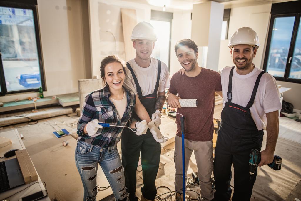 Ein Paar und zwei Handwerker freuen sich über ein gelungenes Projekt.