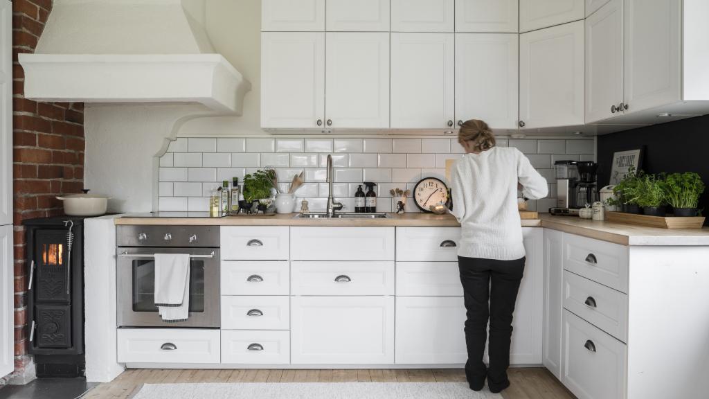 Emma steht in ihrer Küche mit weißen Wandfliesen