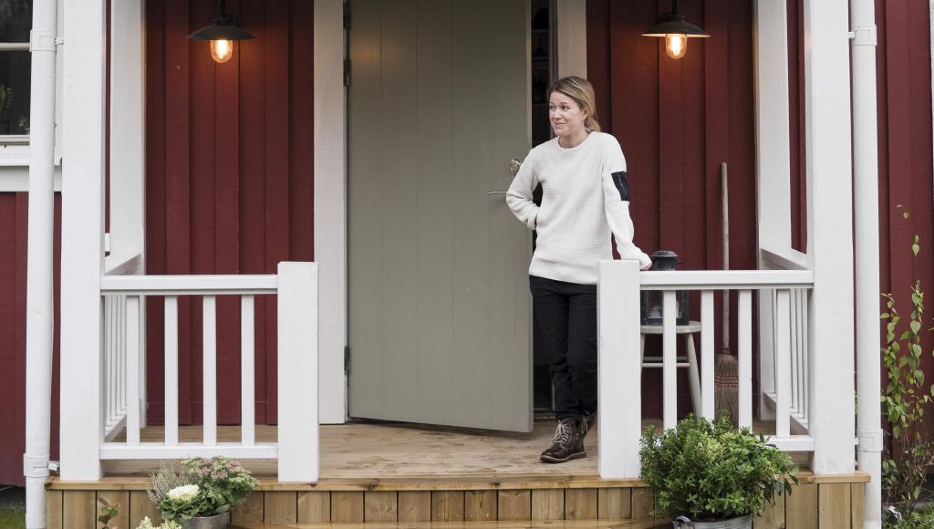 Emma steht auf der Veranda vor ihrem renovierten Raucherhaus.