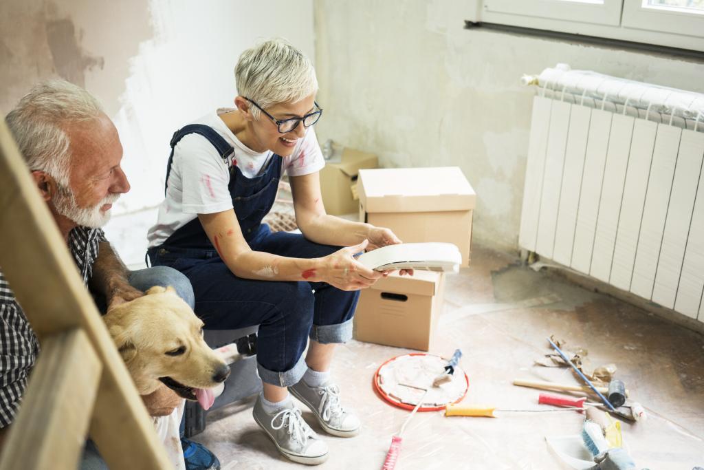 Älteres Paar mit Hund bespricht Modernisierungsmaßnahmen auf der Baustelle