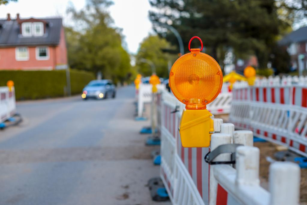 rote und weiße Barrikaden mit Warnlichtern an einer Straße in einem Wohngebiet