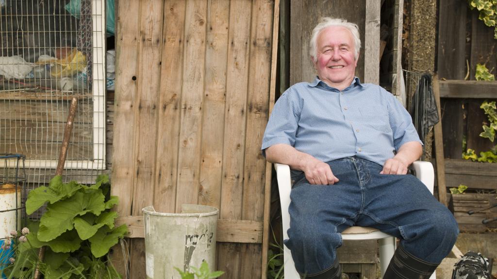 Mythos Schrebergarten: Älterer Mann sitzt vor seiner Laube