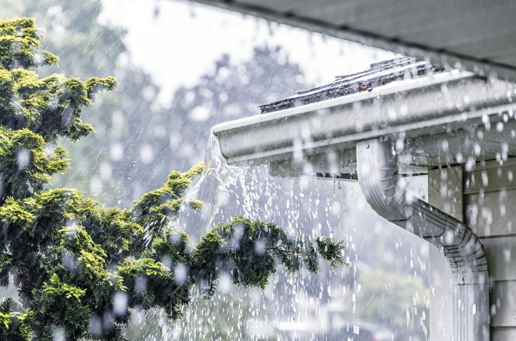 Starker Regen überflutet die Dachrinne eines Hauses