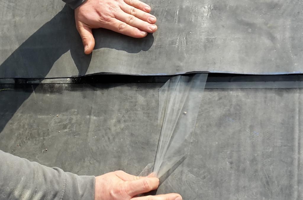 Mann verklebt zwei Bahnen EPDM-Folie übereinander
