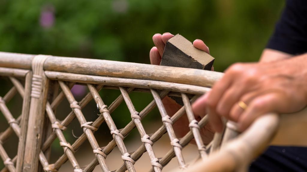 Mann schleift verblassten Rattanstuhl ab