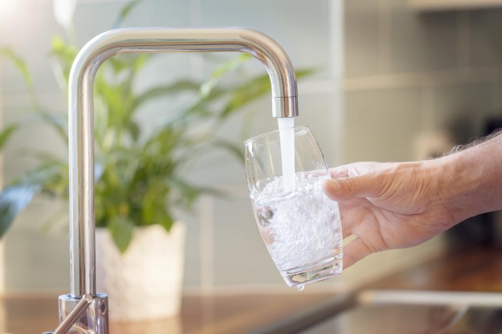 Wasserknappheit: Trinkwasser läuft durch einen Wasserhahn in ein Glas.