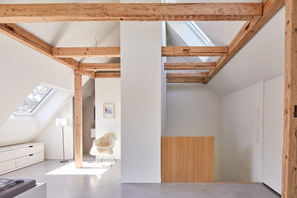 Offene Raumstruktur unter altem Dachgebälk in einem Wohnhaus in Stuttgart.