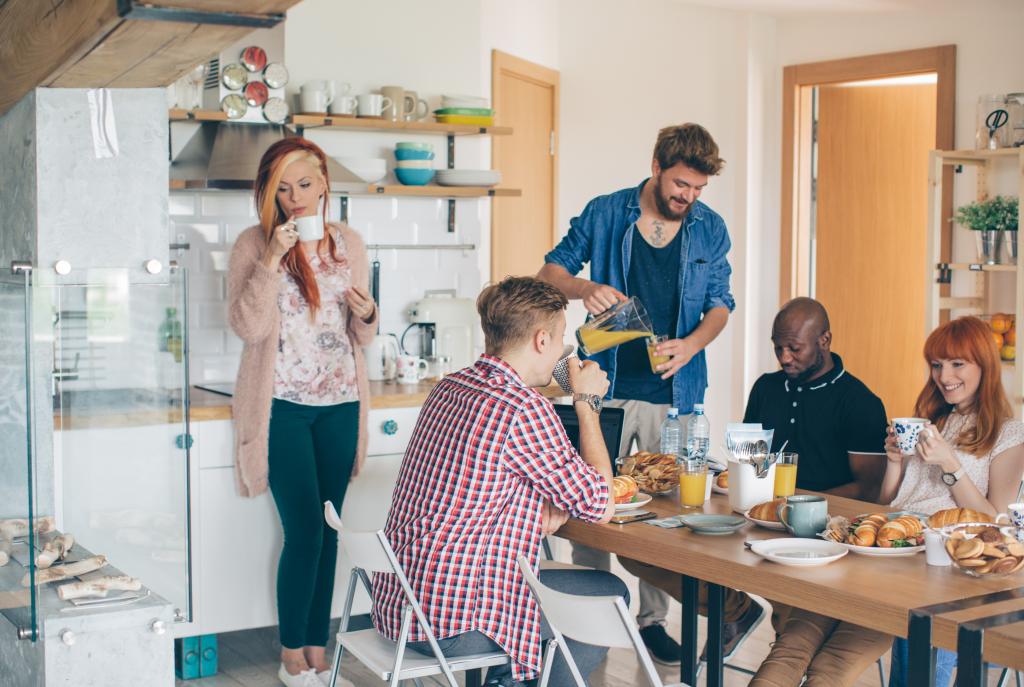 Gruppe junger Leute beim gemeinsamen Frühstück in einer Küche