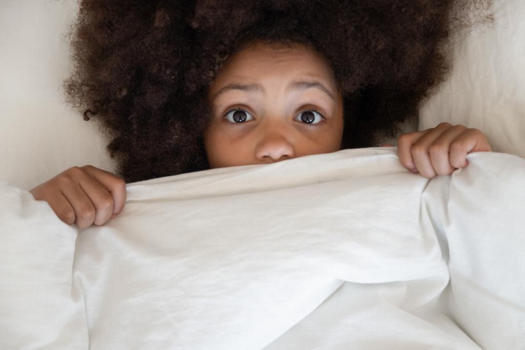 Kind versteckt sich unter Bettdecke