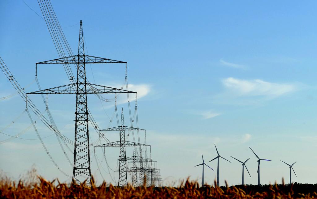 Hochspannungsmasten und Windräder unter blauem Himmel