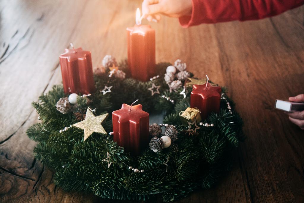 Frau entzündet Kerze auf dem Adventskranz