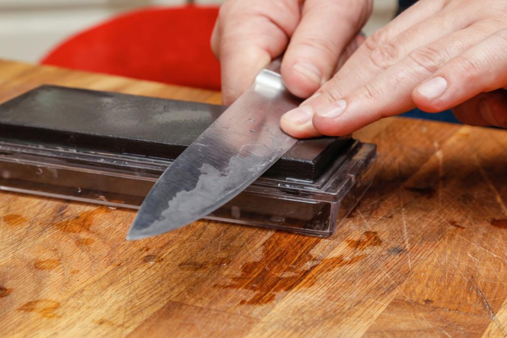 Ein Messer wird auf einem Schleifstein geschärft